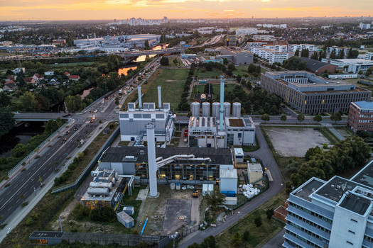 Berlin Germany 07 September 2026 Aerial view of BTB Heizkraftwerk Adlershof a power plant facility surrounded by urban infrastructure roads and greenery at sunset.