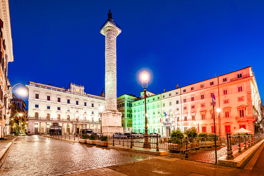 View of the Column of Marcus Aurelius in Piazza Colonna with illuminated historic buildings and the Italian flag colors at night in Rome Lazio Italy. View of the Column of Marcus Aurelius in Piazza Colonna with illuminated historic buildings and the Italian flag colors at night in Rome Lazio Italy.
