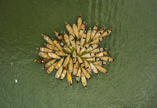 Aerial view of a cluster of wooden boats arranged in a star like pattern on the river in Dhaka Dhaka Division Bangladesh.
