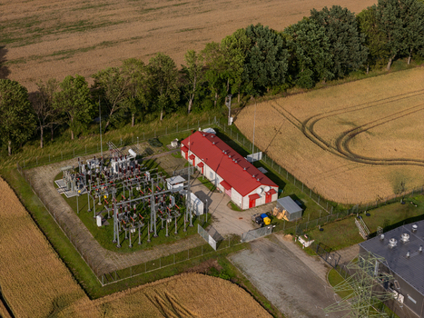 Aerial view of an electrical substation with a red roofed building transformers and power lines surrounded by fields and trees in Gdansk Pomeranian Voivodeship Poland. Aerial view of an electrical substation with a red roofed building transformers and power lines surrounded by fields and trees in Gdansk Pomeranian Voivodeship Poland.