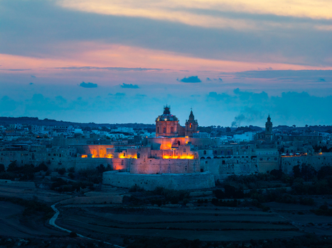 Aerial view of the illuminated historic fortifications and cathedral of Mdina at twilight set against the surrounding landscape in Mdina Western Region Malta. Aerial view of the illuminated historic fortifications and cathedral of Mdina at twilight set against the surrounding landscape in Mdina Western Region Malta.