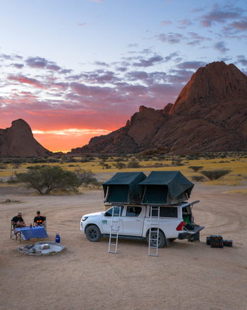 Spitzkoppe Namibia 11 March 2026 Aerial view of a lone white truck with rooftop tents under a vibrant sunset sky framed by the rugged peaks of Spitzkoppe s ancient granite formations. Spitzkoppe Namibia 11 March 2026 Aerial view of a lone white truck with rooftop tents under a vibrant sunset sky framed by the rugged peaks of Spitzkoppe s ancient granite formations.