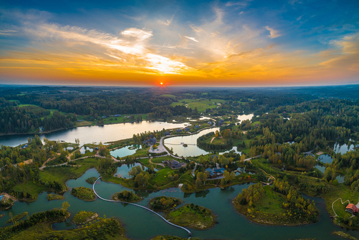 Aerial view of a serene lake landscape with small islands lush forests and winding footpaths under a vibrant sunset sky in Latvia. Aerial view of a serene lake landscape with small islands lush forests and winding footpaths under a vibrant sunset sky in Latvia.