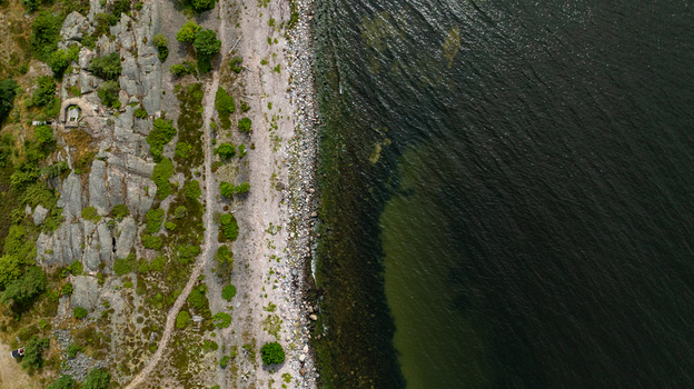Aerial view of Oro Fortress Island featuring rugged rocky terrain a coastal path and dense greenery bordering the dark Baltic Sea waters Oro Varsinais Suomi Finland. Aerial view of Oro Fortress Island featuring rugged rocky terrain a coastal path and dense greenery bordering the dark Baltic Sea waters Oro Varsinais Suomi Finland.