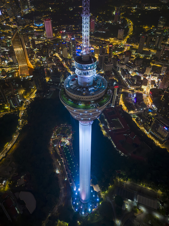 Kuala Lumpur Malaysia 11 March 2026 Aerial view of the illuminated Kuala Lumpur Tower at night with the glowing city skyline and urban streets in the background.