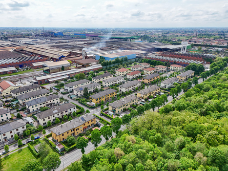 Aerial view of the industrial complex and residential neighborhood with rows of houses and green trees in Dalmine Lombardy Italy. Aerial view of the industrial complex and residential neighborhood with rows of houses and green trees in Dalmine Lombardy Italy.