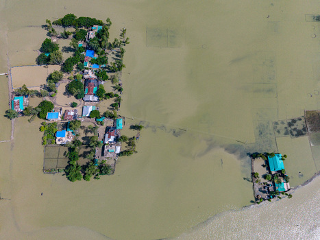 Aerial view of a flooded residential area with houses surrounded by murky floodwaters and lush green trees in Banshkhali Upazila Chittagong Division Bangladesh. Aerial view of a flooded residential area with houses surrounded by murky floodwaters and lush green trees in Banshkhali Upazila Chittagong Division Bangladesh.