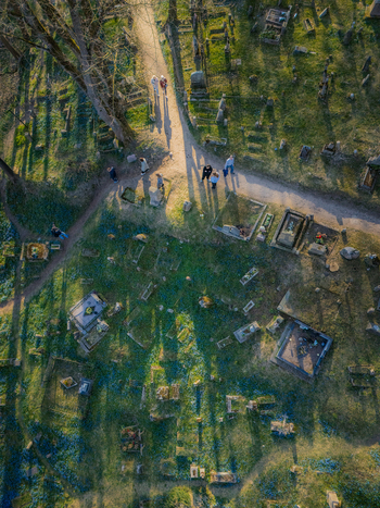 Aerial view of Bernardine Cemetery with people walking along paths historic gravestones and long shadows cast by trees in the golden hour light in Vilnius Vilniaus apskritis Lithuania. Aerial view of Bernardine Cemetery with people walking along paths historic gravestones and long shadows cast by trees in the golden hour light in Vilnius Vilniaus apskritis Lithuania.