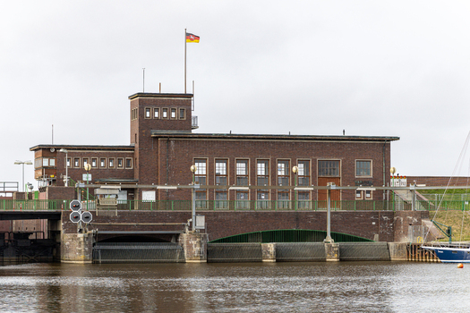 View of the Schleuse Harlesiel brick building and canal under an overcast sky in Wittmund Niedersachsen Germany.