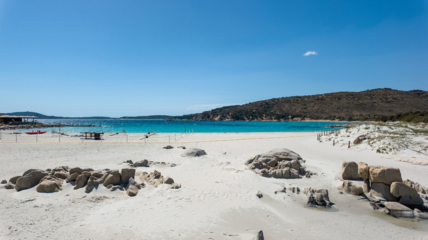 View of Punta Molentis Beach with its white sand turquoise sea and granite rock formations under a clear blue sky in Villasimius Sardinia Italy. View of Punta Molentis Beach with its white sand turquoise sea and granite rock formations under a clear blue sky in Villasimius Sardinia Italy.