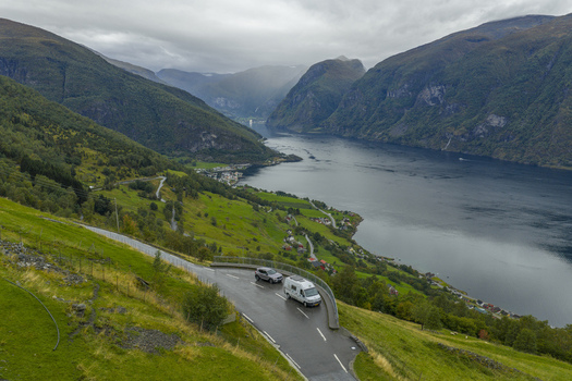 Aerial view of a camper van and car parked at the Aurlandsvangen Viewpoint overlooking the Aurlandsfjord and steep mountains in Aurland Vestland Norway.