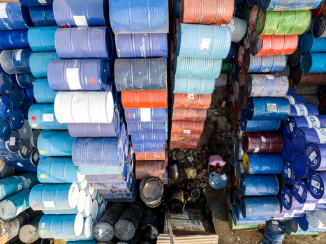 Aerial view of colorful industrial barrels stacked in rows with a worker standing in a narrow alley Dhaka Dhaka Division Bangladesh. Aerial view of colorful industrial barrels stacked in rows with a worker standing in a narrow alley Dhaka Dhaka Division Bangladesh.