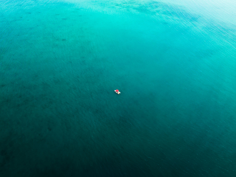 Aerial view of a solitary boat adrift on an endless expanse of turquoise where the ocean s depths meet the sky s embrace Noumea New Caledonia. Aerial view of a solitary boat adrift on an endless expanse of turquoise where the ocean s depths meet the sky s embrace Noumea New Caledonia.