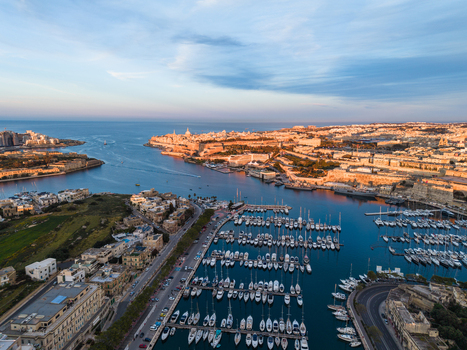 Aerial view of the Grand Harbour in Valletta with rows of yachts in the marina and historic fortifications under a soft blue sky in Malta. Aerial view of the Grand Harbour in Valletta with rows of yachts in the marina and historic fortifications under a soft blue sky in Malta.