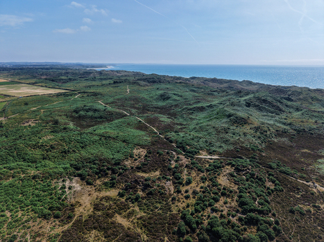 Aerial view of the coastal sand dunes and lush green landscape of Murlough Nature Reserve near the sea in Newcastle Northern Ireland United Kingdom. Aerial view of the coastal sand dunes and lush green landscape of Murlough Nature Reserve near the sea in Newcastle Northern Ireland United Kingdom.