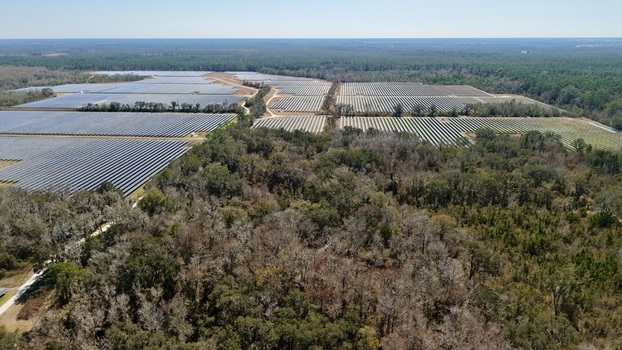 Aerial view of extensive solar panel arrays glinting under the sun bordered by dense woodlands and open fields Elkton Florida United States. Aerial view of extensive solar panel arrays glinting under the sun bordered by dense woodlands and open fields Elkton Florida United States.