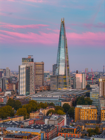Aerial view of The Shard skyscraper rising above the urban landscape at sunset with pink clouds and city buildings in London England United Kingdom.