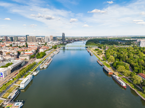 Aerial view of the Danube river flowing through the city with bridges riverboats and modern skyscrapers under a blue sky in Bratislava Bratislava Region Slovakia. Aerial view of the Danube river flowing through the city with bridges riverboats and modern skyscrapers under a blue sky in Bratislava Bratislava Region Slovakia.