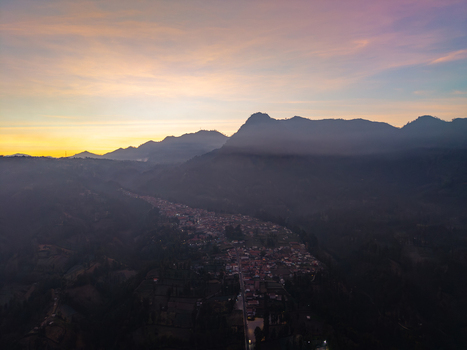 Aerial view of Wonotoro village nestled in the valley during sunset with surrounding mountains and soft golden light in Sukapura East Java Indonesia.