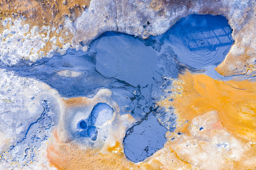 Aerial view of Hverir geothermal field with vibrant blue mud pools and colorful mineral deposits in the volcanic landscape Reykjahlid Thingeyjarsveit Iceland.