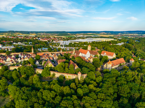 Aerial view of the historic medieval town of Rothenburg ob der Tauber with defensive walls red tiled rooftops and a ferris wheel in Rothenburg ob der Tauber Bavaria Germany. Aerial view of the historic medieval town of Rothenburg ob der Tauber with defensive walls red tiled rooftops and a ferris wheel in Rothenburg ob der Tauber Bavaria Germany.