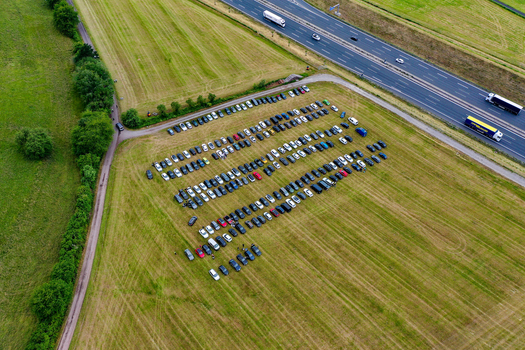 Aerial view of Heroes Festival Geiselwind parking area with rows of cars on a green field next to a busy highway Geiselwind Bayern Germany.