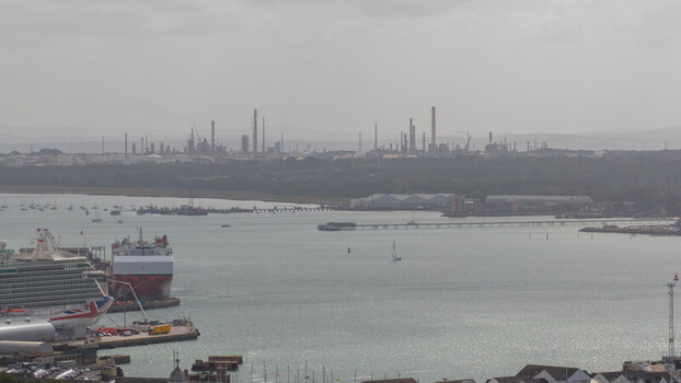 Aerial view of the port of Southampton with cruise ships docked at the terminal industrial refinery towers in the distance and calm waters in Southampton England United Kingdom. Aerial view of the port of Southampton with cruise ships docked at the terminal industrial refinery towers in the distance and calm waters in Southampton England United Kingdom.