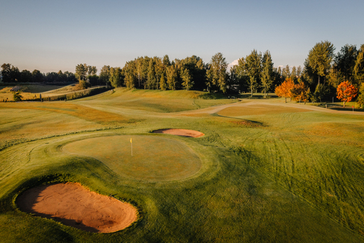 Aerial view of a golf course featuring green fairways sand bunkers and surrounding trees during golden hour in Valmiera Valmiera Latvija.