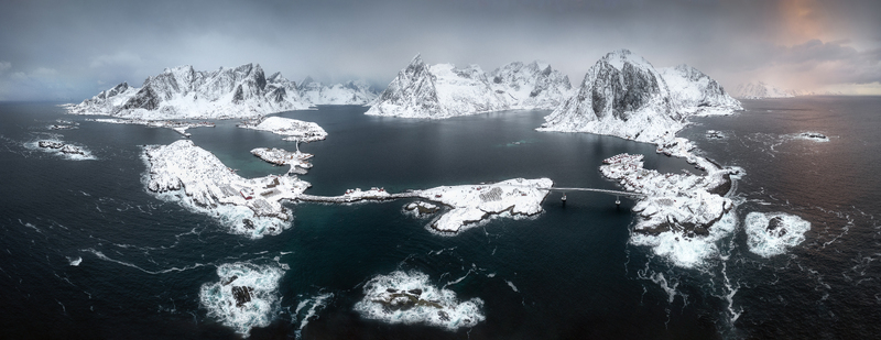 Aerial view of the snow covered Lofoten islands with bridges connecting rocky shores under a dramatic winter sky in Nordland Norway. Aerial view of the snow covered Lofoten islands with bridges connecting rocky shores under a dramatic winter sky in Nordland Norway.