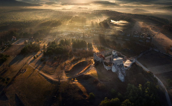 Aerial view of the historic Bobolice Castle ruins perched on a limestone cliff amidst misty forests and golden sunbeams during sunrise Krakow County Lesser Poland Voivodeship Poland. Aerial view of the historic Bobolice Castle ruins perched on a limestone cliff amidst misty forests and golden sunbeams during sunrise Krakow County Lesser Poland Voivodeship Poland.