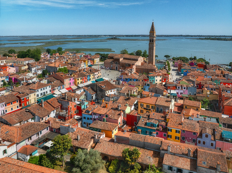 Aerial view of a vibrant tapestry of colorful houses and the iconic leaning bell tower of Burano under a clear blue sky Venice Veneto Italy. Aerial view of a vibrant tapestry of colorful houses and the iconic leaning bell tower of Burano under a clear blue sky Venice Veneto Italy.