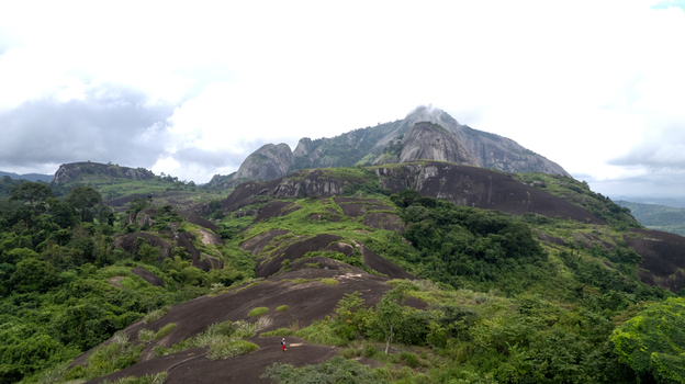 Aerial view of Idanre Hill with its dramatic granite inselbergs lush green vegetation and rocky terrain under a cloudy sky in Idanre Ondo State Nigeria. Aerial view of Idanre Hill with its dramatic granite inselbergs lush green vegetation and rocky terrain under a cloudy sky in Idanre Ondo State Nigeria.