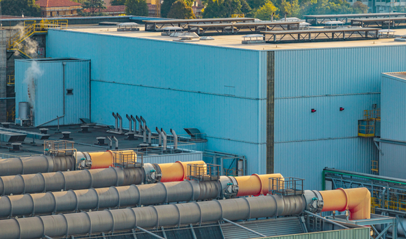 Aerial view of industrial ventilation and exhaust duct network connected to a large manufacturing building at a heavy industry production facility in Brescia Lombardy Italy.