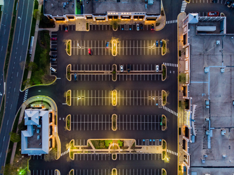 Reston Virginia United States 12 April 2020 Aerial view of a commercial parking lot at dusk with illuminated street lights marked spaces and retail buildings.