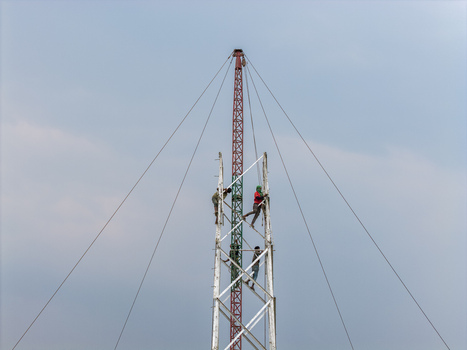 Trishal Upazila Bangladesh 13 May 2026 Aerial view of workers climbing a tall telecommunications tower structure under a clear sky. Trishal Upazila Bangladesh 13 May 2026 Aerial view of workers climbing a tall telecommunications tower structure under a clear sky.