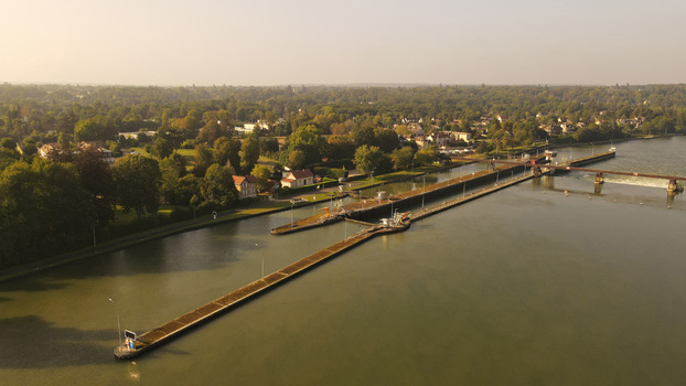 Aerial view of the river lock and dam on the Seine river surrounded by lush greenery and trees in Chartrettes Ile de France France. Aerial view of the river lock and dam on the Seine river surrounded by lush greenery and trees in Chartrettes Ile de France France.