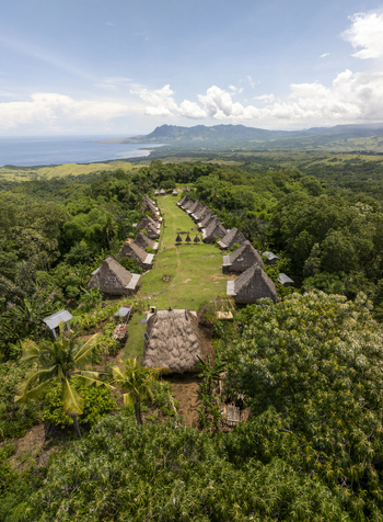 Aerial view of Kampung Adat Belaraghi with traditional houses along a central path surrounded by lush forest and coastal hills in Kecamatan Aimere Nusa Tenggara Timur Indonesia. Aerial view of Kampung Adat Belaraghi with traditional houses along a central path surrounded by lush forest and coastal hills in Kecamatan Aimere Nusa Tenggara Timur Indonesia.