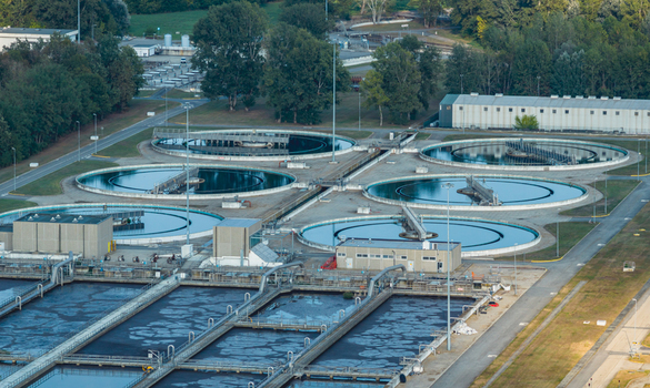 Aerial view of circular clarifiers and aeration basins at a large wastewater treatment facility in Italy.