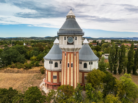 Aerial view of the restored historic gasworks tower at the former Obuda Gasworks rising above trees and residential neighborhoods in Budapest Hungary on a summer day. Aerial view of the restored historic gasworks tower at the former Obuda Gasworks rising above trees and residential neighborhoods in Budapest Hungary on a summer day.