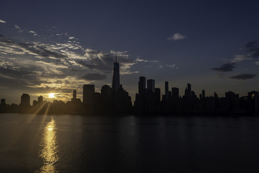 Aerial view of the New York skyline silhouetted against a dramatic sunset with golden light reflecting on the water in New York New York United States.