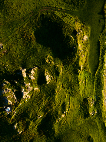 Aerial view of the rugged green landscape and rocky outcrops near Tangstad during golden hour in Leknes Nordland Norway. Aerial view of the rugged green landscape and rocky outcrops near Tangstad during golden hour in Leknes Nordland Norway.