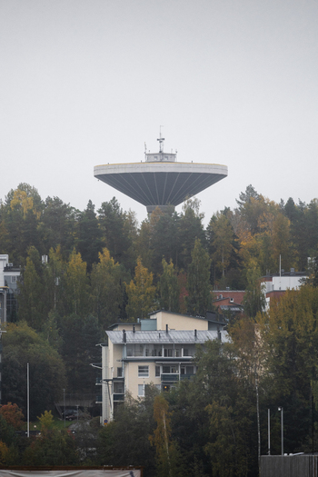 View of the iconic mushroom shaped water tower rising above a dense forest of autumn trees and residential buildings in Jyvaskyla Central Finland Finland.
