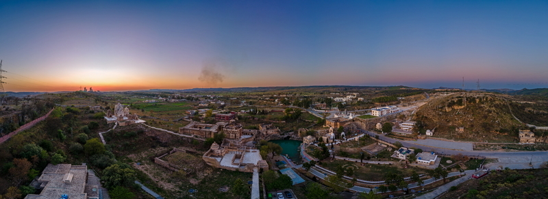 Aerial view of the historic Katas Raj Temple Complex featuring its sacred pond and ancient stone structures surrounded by the rolling hills in Katas Punjab Pakistan. Aerial view of the historic Katas Raj Temple Complex featuring its sacred pond and ancient stone structures surrounded by the rolling hills in Katas Punjab Pakistan.