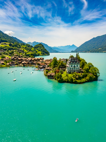 Aerial view of the shimmering turquoise waters embracing a quaint island village and the majestic Schloss Iseltwald a scene of serene beauty Iseltwald Canton of Bern Switzerland. Aerial view of the shimmering turquoise waters embracing a quaint island village and the majestic Schloss Iseltwald a scene of serene beauty Iseltwald Canton of Bern Switzerland.