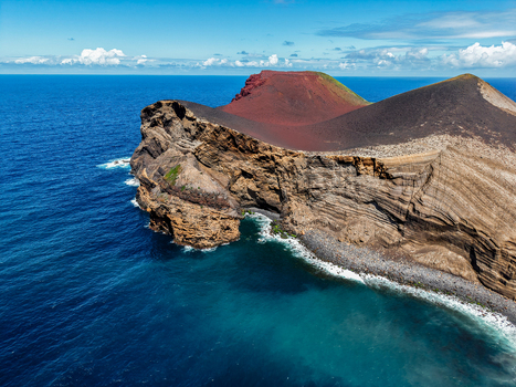 Aerial view of the rugged coastline meets the deep blue sea where the volcanic landscape rises dramatically Capelo A&ccedil;ores Portugal.
