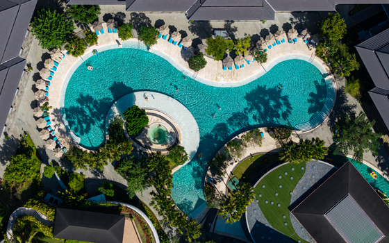 Aerial view of the swimming pool at Marriott s Bali Nusa Dua Gardens with lush tropical landscaping sun loungers and palm trees in Kecamatan Kuta Selatan Bali Indonesia.