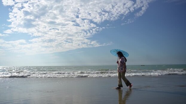 View of a woman walking with an umbrella on the beach Bangladesh. View of a woman walking with an umbrella on the beach Bangladesh.