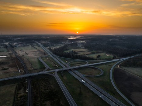 Aerial view of the A5 and A8 highway interchange at sunset with golden light reflecting on the asphalt and surrounding rural landscape in Olaine Parish Olaine Municipality Latvia. Aerial view of the A5 and A8 highway interchange at sunset with golden light reflecting on the asphalt and surrounding rural landscape in Olaine Parish Olaine Municipality Latvia.