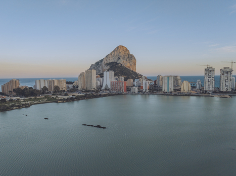 Aerial view of the iconic Penon de Ifach rising above the coastal town with modern apartment buildings and the Mediterranean Sea in Calp Valencian Community Spain. Aerial view of the iconic Penon de Ifach rising above the coastal town with modern apartment buildings and the Mediterranean Sea in Calp Valencian Community Spain.