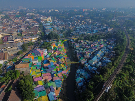 Aerial view of Kampung Warna Warni Jodipan with vibrant multi colored houses lining the riverbanks crossed by a bridge near a railway track in Kecamatan Blimbing Jawa Timur Indonesia. Aerial view of Kampung Warna Warni Jodipan with vibrant multi colored houses lining the riverbanks crossed by a bridge near a railway track in Kecamatan Blimbing Jawa Timur Indonesia.